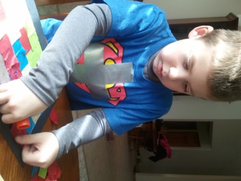 Jackson works on glueing color strips on his cross suncatcher. He has a cross duct-taped to his shirt because that is the AWANA theme at church.