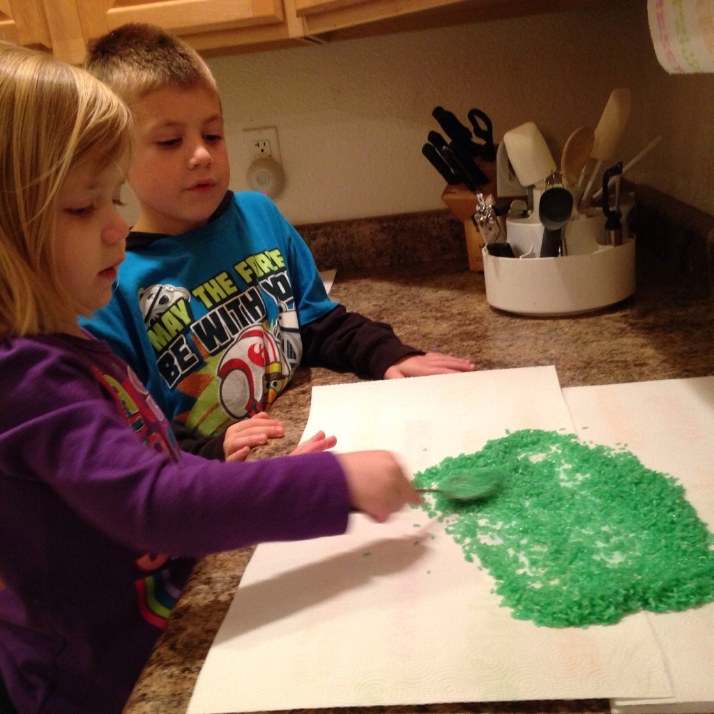 Lauren spreads our her green rice to dry while Jackson watches.