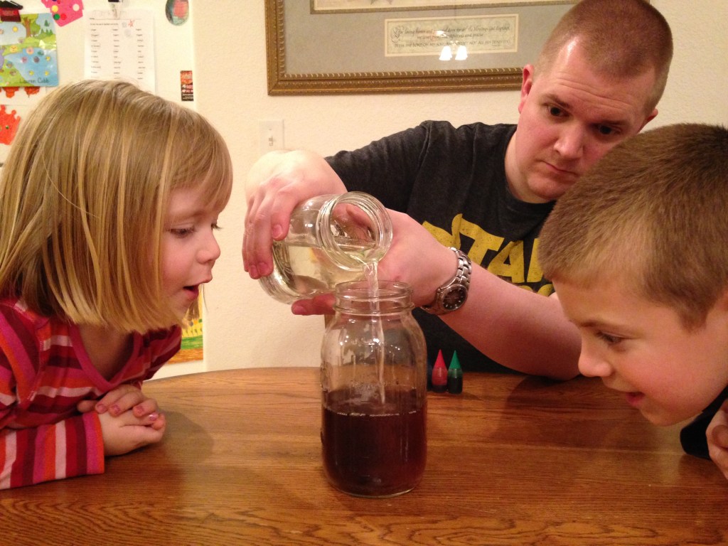 Jackson and Lauren watch as the water filled with sin (food coloring drops) becomes clean when the Jesus jar is poured in.
