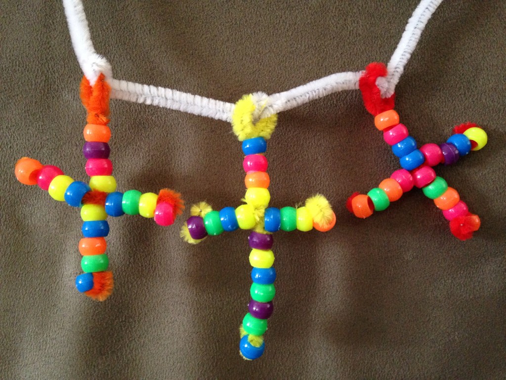A close-up of the Three Cross Bead Necklace. This simple craft project is easy to modify and great for young toddlers with supervision or grade schoolers who want to be creative.