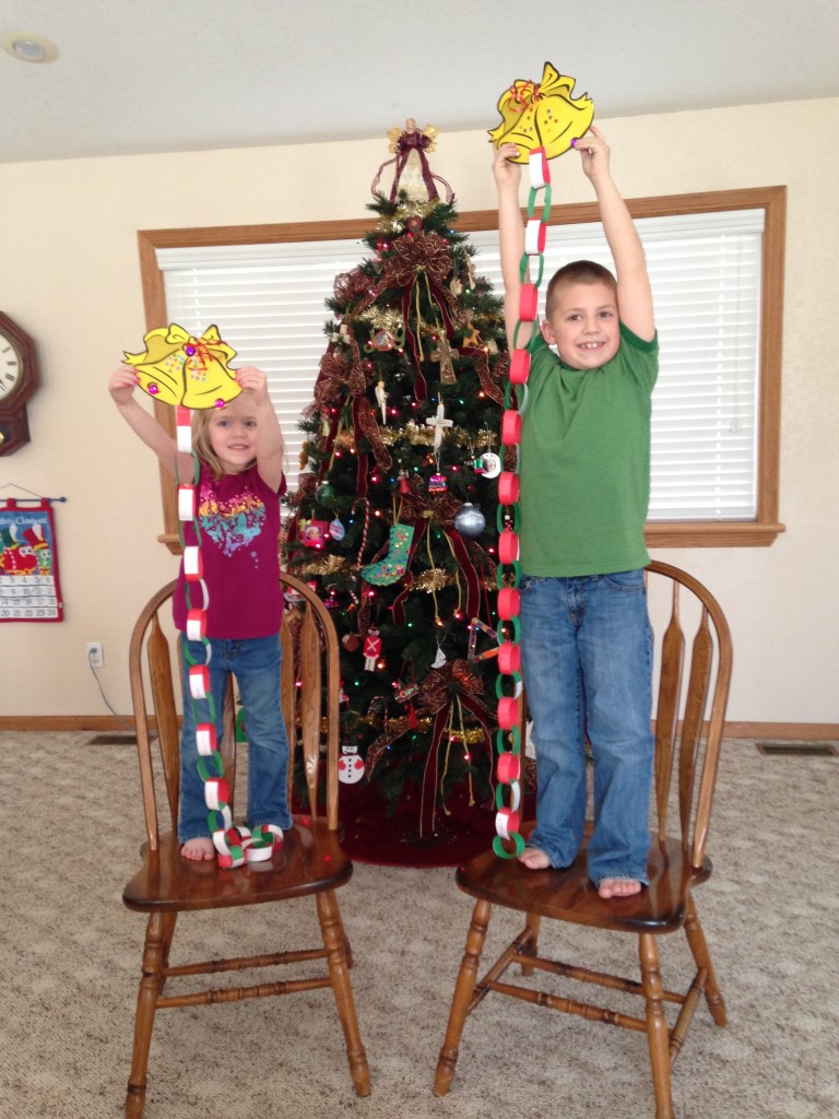 The kids hold their Christmas prayer chains high. Each day we will pray to our Father God for one person as we countdown to Jesus's birthday.